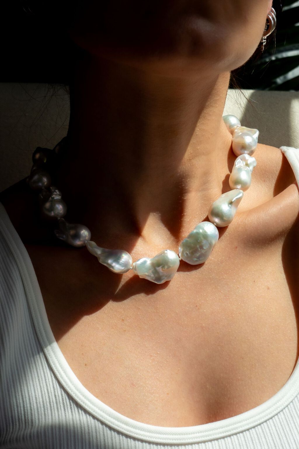 Woman in white tank top wearing baroque pearls
